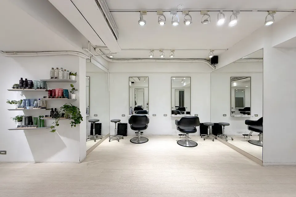 沙龍內明亮的白色空間,牆面層架陳列 Aveda 髮品與綠植