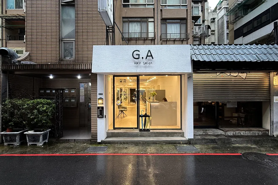 G.A Hair Salon 忠孝東路 216 巷店面外觀,雨後夜色中的白色招牌與明亮落地窗